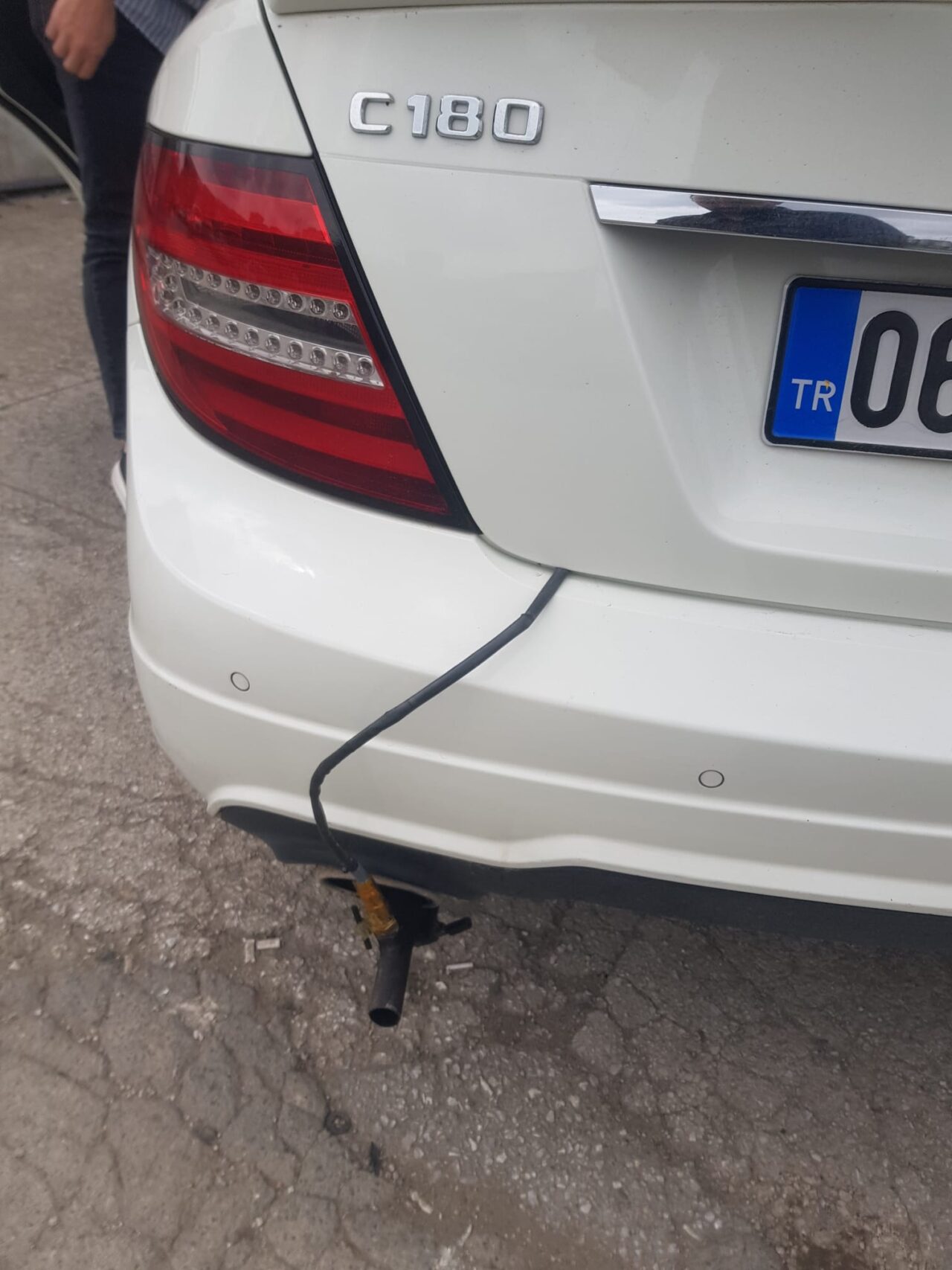 Beyaz Mercedes C180'in egzozuna takılmış geniş bant AFR sensörü ve kablosu